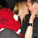 Coppia si bacia durante un felice anniversario festeggiato con sorpresa di rose rosse e limousine