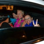 Donne con boa di struzzo colorati festeggiano divertite nella limousine